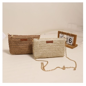 Detail of square woven straw crossbody bags in brown and cream with gold chain straps