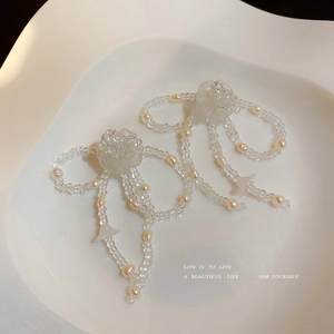 Elegante Perlen-Schleifenohrringe mit Perlen und mattierter Blume auf weißem Tablett