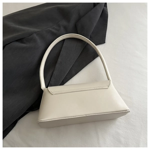 Detail showing solid cream PU leather material and magnetic closure on minimalist baguette bag