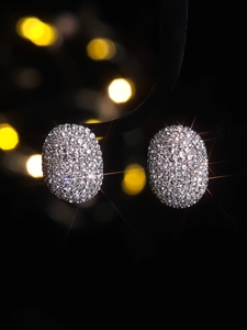 Vue macro de boucles d'oreilles ovales avec cristaux pavés sur fond bokeh noir