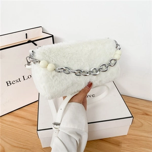 Detail of white plush bucket bag with silver chain and decorative oversized pearls