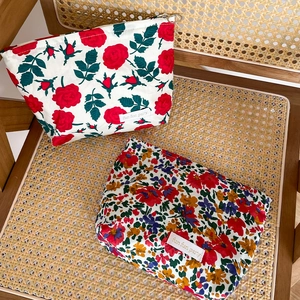 Floral print canvas makeup bags with zip closure and vintage rose pattern on a woven chair