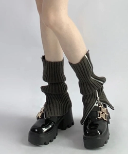 Gros plan sur les jambières en maille vert olive avec fermeture éclair et chaussures