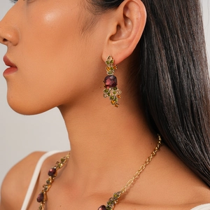 Close-up of vintage gold floral earrings with crimson square stones and colorful crystals