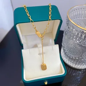 Close-up of a gold titanium Lucky tassel necklace on a vintage green jewelry box