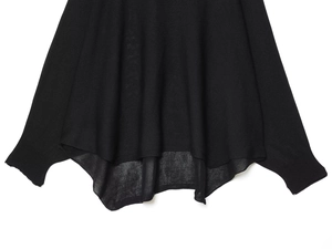Close-up of black knitted sweater showing fabric texture and irregular wave hem design