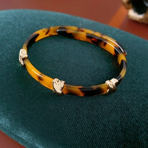 Detail of leopard print resin bangle with gold metallic accents on green velvet