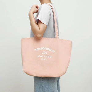 Pink canvas tote bag featuring white slogan print and wide shoulder strap detail