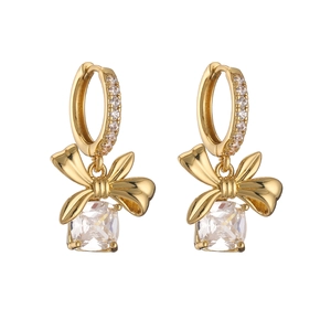 Macro detail of gold bow earrings with micro-paved diamonds and clear square crystal drops