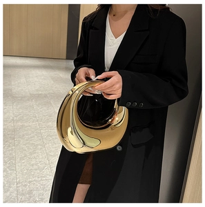Primer plano de un bolso de mano de acrílico espejo dorado en forma de media luna