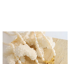 Detailed macro view of irregular off-white pearls with a golden bow-shaped metal clasp