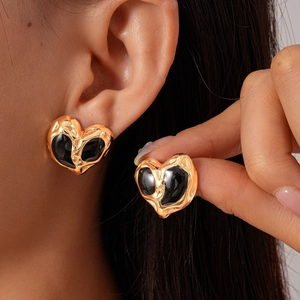 Detail of vintage heart earrings with textured gold metal and black enamel finish