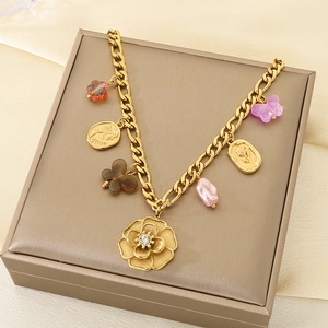 Detailed close-up of golden Cuban chain bracelet with floral charms and colorful beads