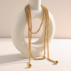 Layered 18K gold plated stainless steel necklace draped over a white ceramic vase