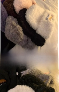 Detail of plush faux fur beanie with embroidered letters in various winter colors