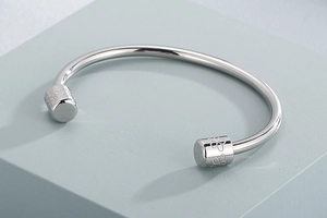 Detailed macro of polished silver cuff bangle with engraved floral cylindrical tips