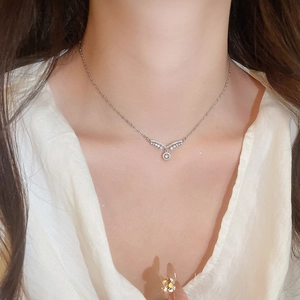 Gros plan du collier pendentif en V argenté avec cristaux de zircon brillants sur modèle