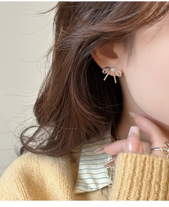 Close-up of elegant bow-shaped earrings and matching ring on model in silver finish