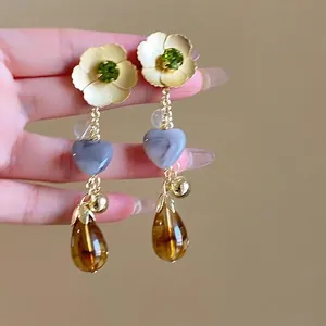 Detail of flower tassel earring with green gemstone, cream petals and amber waterdrop
