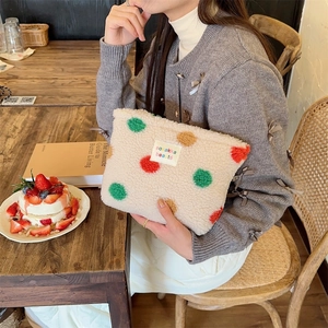 Close-up of cream fleece makeup bag with colorful polka dots and branding label