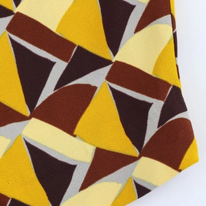 Dettaglio del tessuto con motivi geometrici sul set camicia e pantaloni ampi vintage