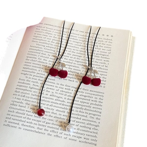 Flocked cherry pendant necklace with pearls and red beads on a vintage book backdrop