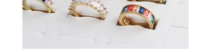 Detailed macro view of gold rings with colorful rectangular zircon stones in a display box
