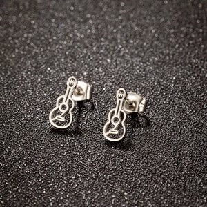 Silver hollow guitar stud earrings in stainless steel on black textured background