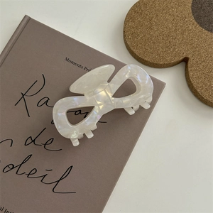 Dettaglio di un fermaglio per capelli bianco perlato su sfondo di un libro vintage