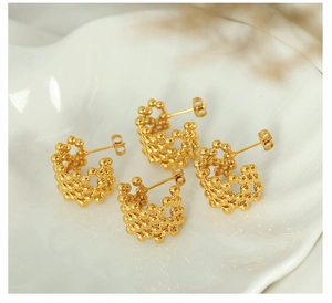 Detail showing two pairs of C-shaped 18K gold plated mesh earrings on white silk fabric