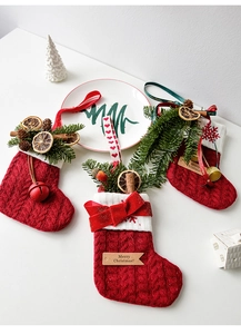 Detalle de calcetines navideños de punto rojo con ramas de pino, campanas y canela