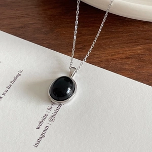 Detailed shot of 925 sterling silver necklace featuring oval black onyx puzzle pendant