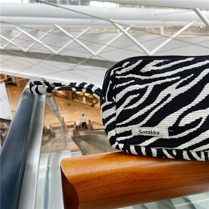 Détail d'une trousse de maquillage en toile à motif zèbre avec étiquette tissée
