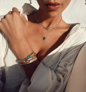 Detailansicht von Goldketten und Armbändern mit grünen Smaragd-Herzanhängern