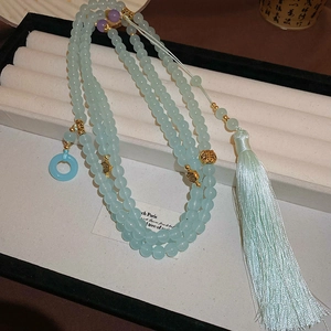Detail view of light cyan glass prayer beads with tassel for traditional dress