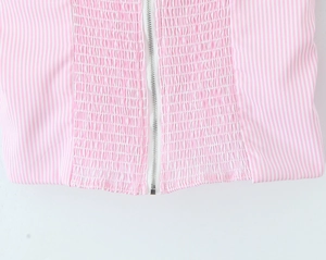 Macro view of pink and white striped fabric with smocked texture and silver metal zipper