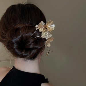Detailed close-up of golden flower hair pin with textured petals and delicate tassels