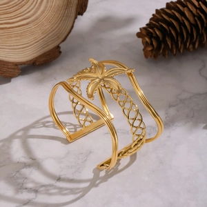 Detailed view of wide hollow gold cuff with palm tree motif for tropical vacation style
