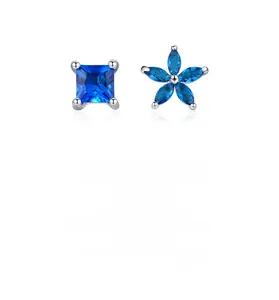 Macro shot of asymmetric S925 silver studs with blue flower and square sapphire stones