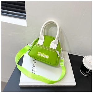 Detail of neon green kids mini handbag with white handle and Tochaso letter patch