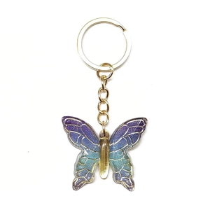 Macro detail of gradient butterfly keychain with gold edges and sparkling glitter finish