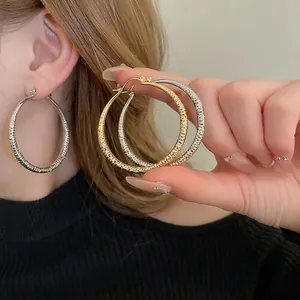 Textured round metal hoop earrings in gold and silver finish with hammer pattern