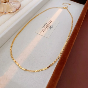 Golden mariner chain necklace displayed on a brown tray with soft natural lighting