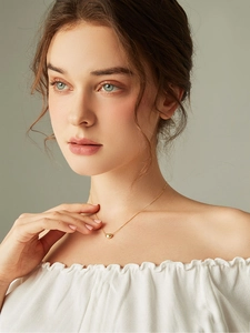 Close-up of a minimalist gold bean pendant necklace worn by a model on a neutral background