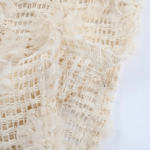 Dettaglio del tessuto beige testurizzato con rete di pizzo e ricami floreali 3D