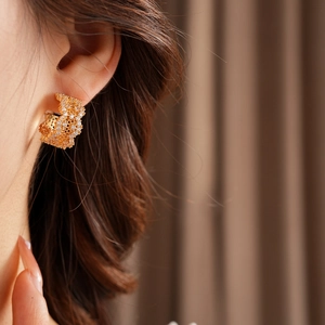 Detailed view of wide C-shaped gold earrings featuring a dense cubic zirconia honeycomb design