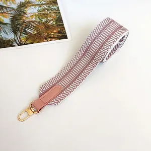 Close-up of pink and white woven shoulder strap with leather end and gold metal hook