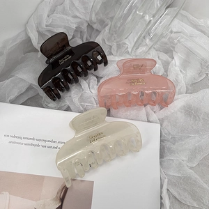 Detailed trio of dark brown, pink, and beige acrylic shark hair claws on white fabric