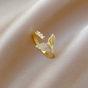 Adjustable gold fishtail ring with white zircons on champagne silk background