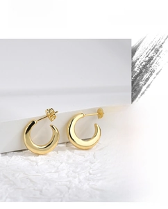 Detailed view of thick gold C-shaped hoop earrings with a high-polished metallic finish